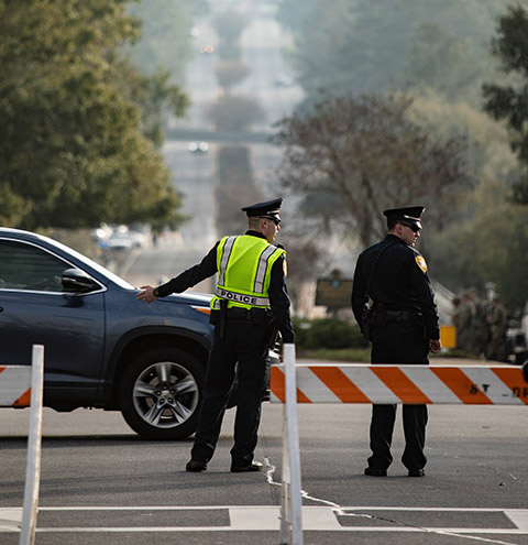 Officers work a closed intersection on a street during a public event